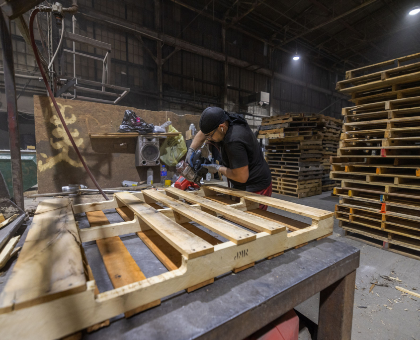 Man working on pallet with hand tool.